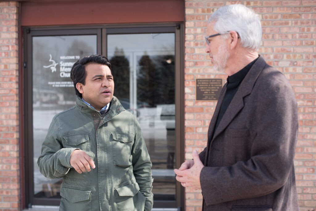 Naun Cerrato and Charles Geiser talk outside Sunnyside Mennonite Church. Photo by David Fast.