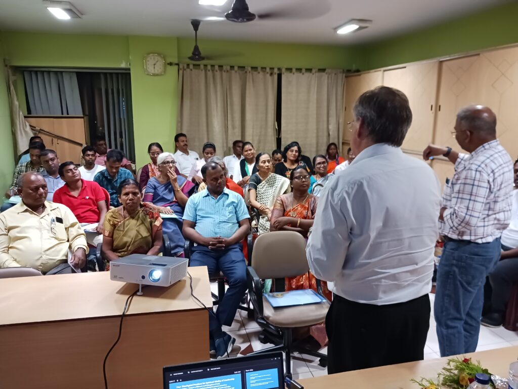 David Boshart and Vikal Pravin Rao look on while Sangita Tigga of Bihar Mennonite Mandli conference reports from a small group.