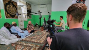 Naylul Maraam Islamic Center is a Quranic school in Harlem, founded and led by Ustaz Abdou Mbaye (far left). Jonathan Bornman is interviewing Serigne Afia Niang. Director of Photography Ehab Assal is seated at camera and crew member Josh Feezer is standing, on the second camera. Photo by D. Michael Hostetler.