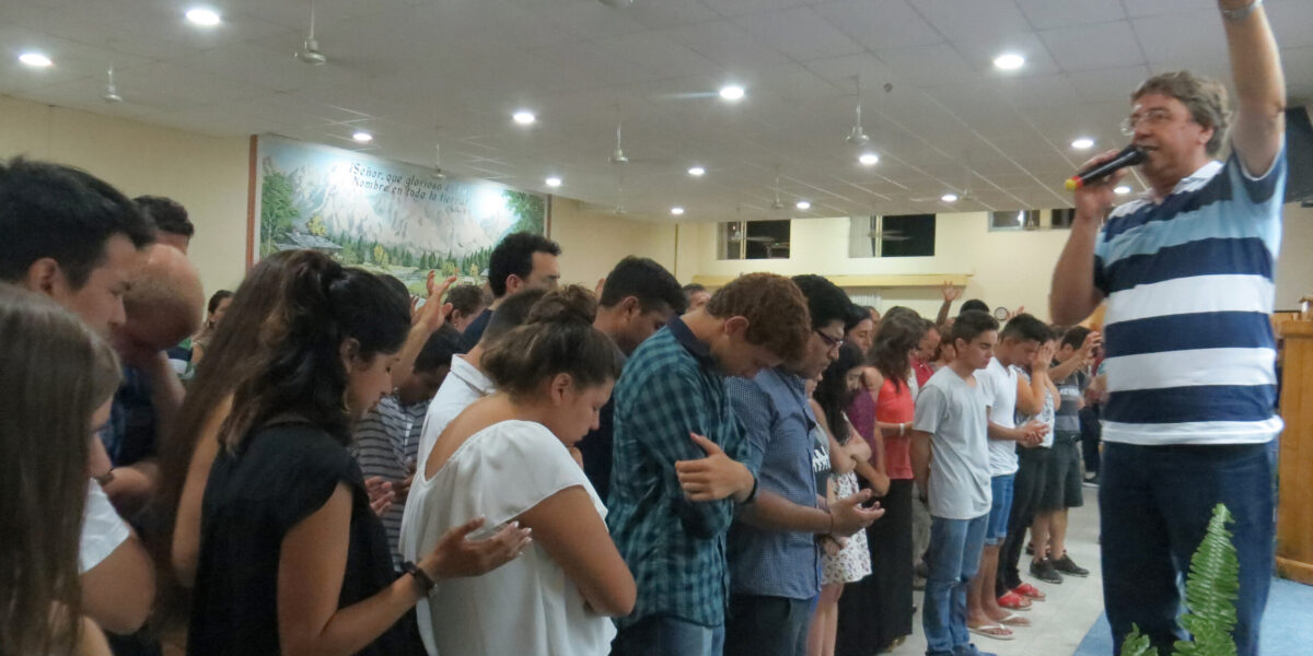 ​Pastor Daniel Oyanguren prays for youth and young adults who came forward in response to a missionary call at the January assembly of the Iglesia Evangélica Menonita Argentina (IEMA) in Choele Choel. The IEMA sends missionary church planters to share God's good news throughout the country. Photo by Linda Shelly.