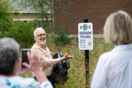 ​Dr. Luke Gascho unveils one of the four trail signs that were installed on the Anabaptist Mennonite Biblical Seminary campus on Sept. 29. Photographer: David Fast.