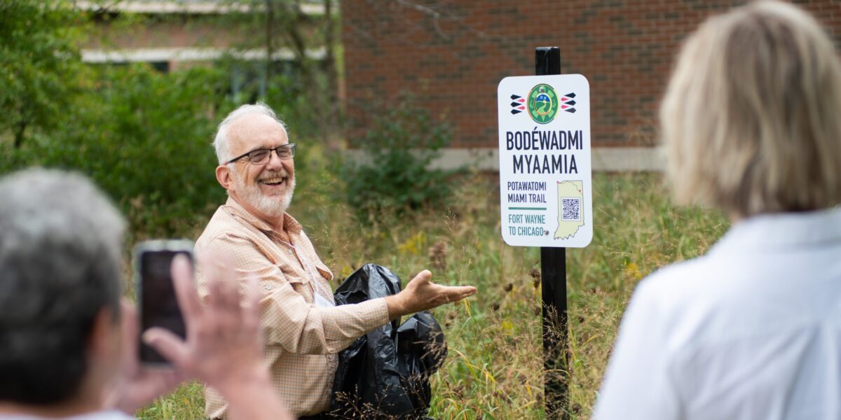 ​Dr. Luke Gascho unveils one of the four trail signs that were installed on the Anabaptist Mennonite Biblical Seminary campus on Sept. 29. Photographer: David Fast.