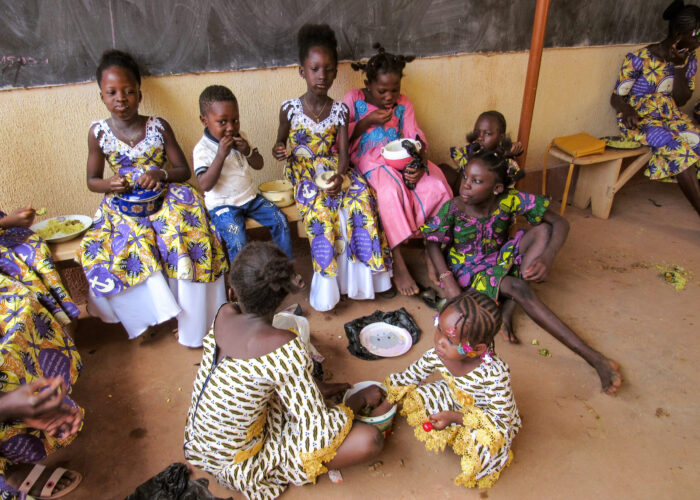 ​Children in Burkina Faso commune together around shared plates of food. Photo provided.