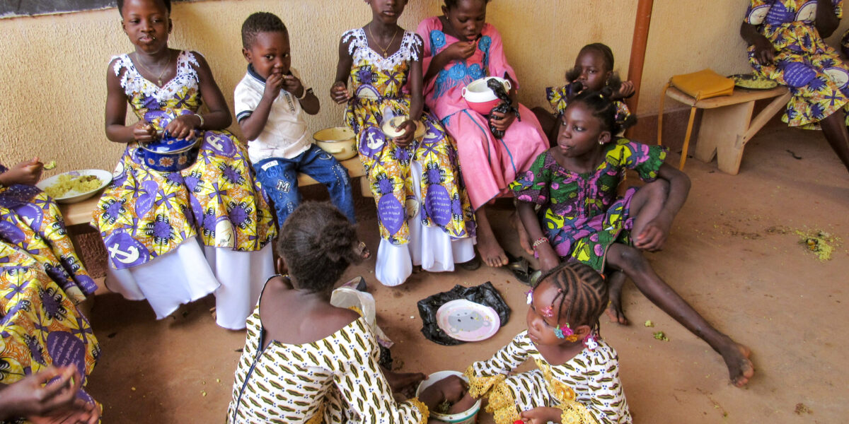 ​Children in Burkina Faso commune together around shared plates of food. Photo provided.