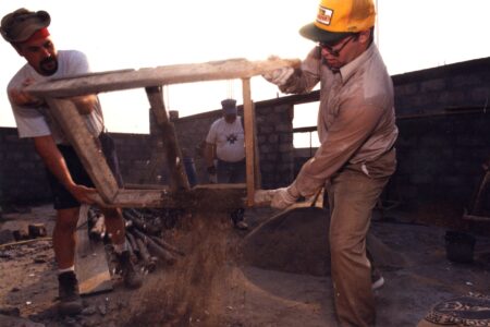 After mixing sand and cement by hand and sifting out rocks and other debris