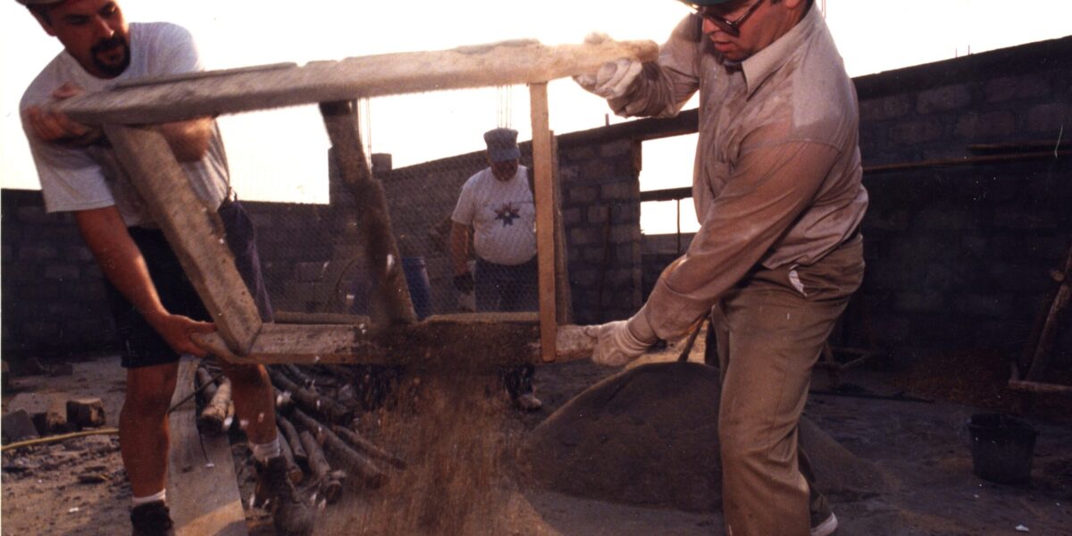 After mixing sand and cement by hand and sifting out rocks and other debris