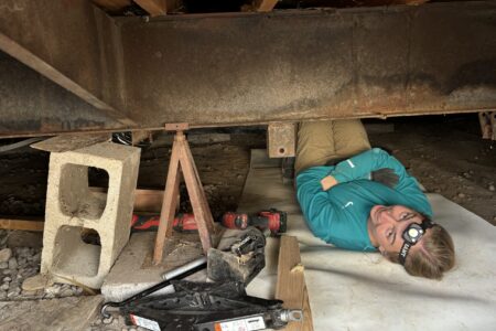 Hannah Lehman works underneath a mobile home.