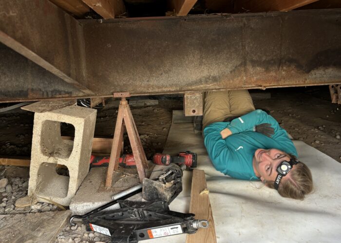 Hannah Lehman works underneath a mobile home.