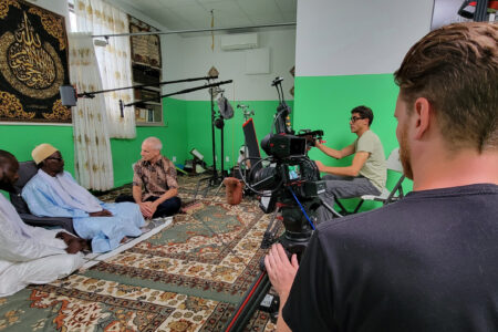 Naylul Maraam Islamic Center is a Quranic school in Harlem, founded and led by Ustaz Abdou Mbaye (far left). Jonathan Bornman is interviewing Serigne Afia Niang. Director of Photography Ehab Assal is seated at camera and crew member Josh Feezer is standing, on the second camera. Photo by D. Michael Hostetler.