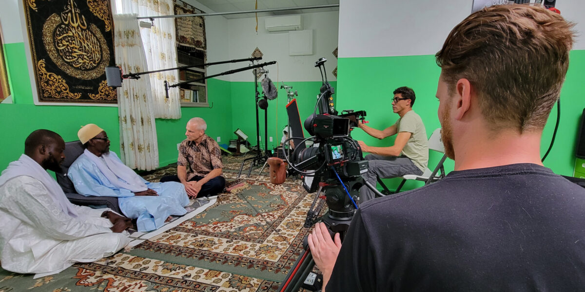 Naylul Maraam Islamic Center is a Quranic school in Harlem, founded and led by Ustaz Abdou Mbaye (far left). Jonathan Bornman is interviewing Serigne Afia Niang. Director of Photography Ehab Assal is seated at camera and crew member Josh Feezer is standing, on the second camera. Photo by D. Michael Hostetler.