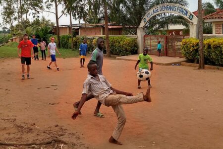 Armel Gladja and Gildas Akpo kick the ball during an afternoon soccer game between Youth Venture participants and children