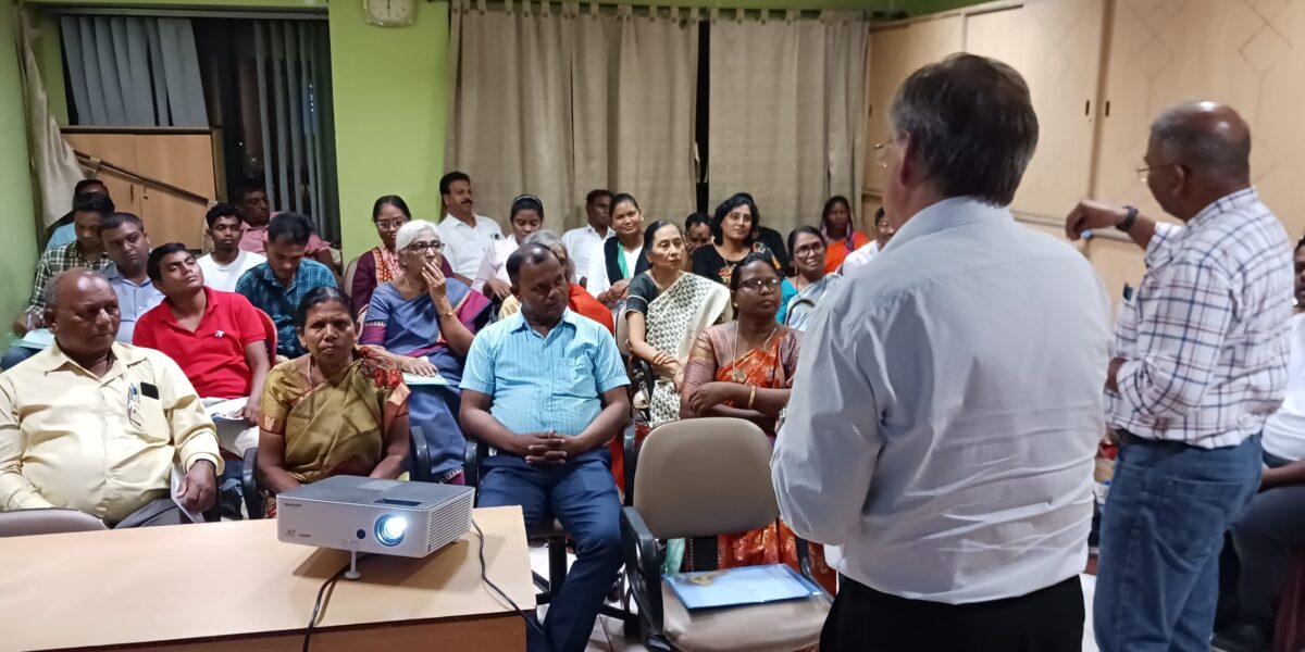 David Boshart and Vikal Pravin Rao look on while Sangita Tigga of Bihar Mennonite Mandli conference reports from a small group.